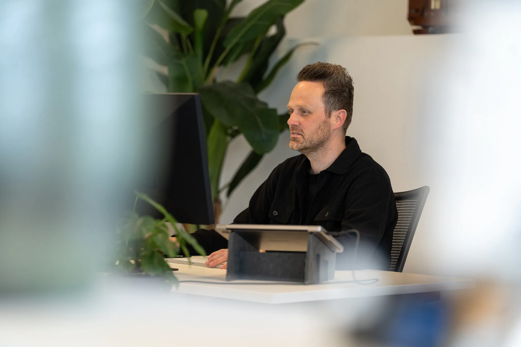 Collega werkt geconcentreerd achter een tablet aan zijn bureau