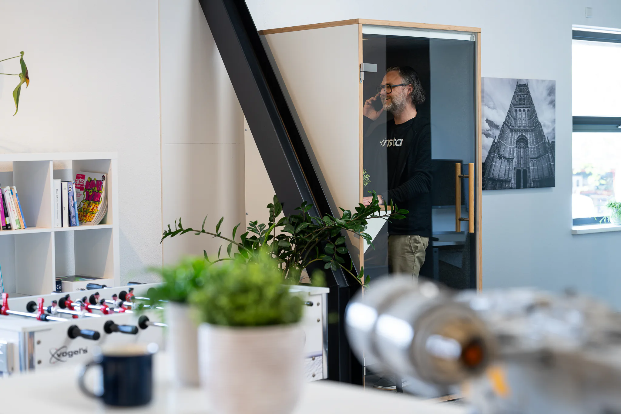 Collega belt in de telefooncel van het kantoor, met planten op de voorgrond